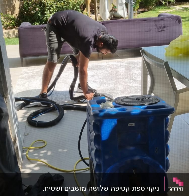 אדם מנקה שטיח עם מכונת ניקוי חיצונית